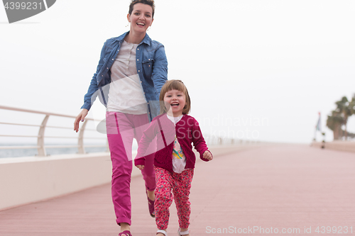 Image of mother and cute little girl on the promenade by the sea