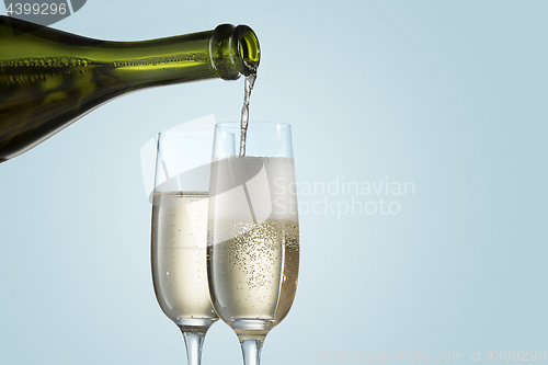 Image of Glasses with champagne and bottle over sparkling holiday background