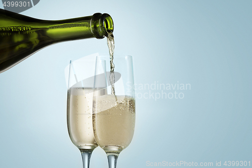 Image of Glasses with champagne and bottle over sparkling holiday background