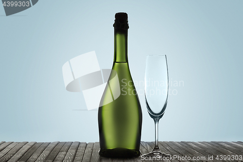 Image of Glasses with champagne and bottle over sparkling holiday background