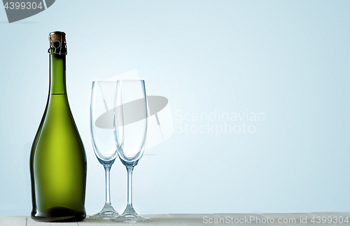 Image of Glasses with champagne and bottle over sparkling holiday background