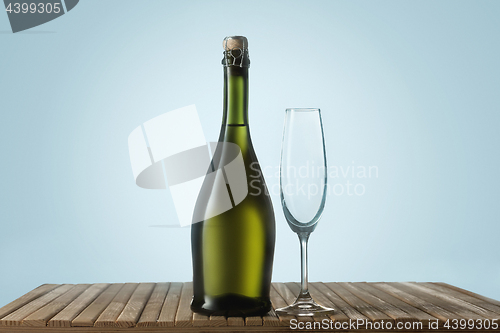 Image of Glasses with champagne and bottle over sparkling holiday background