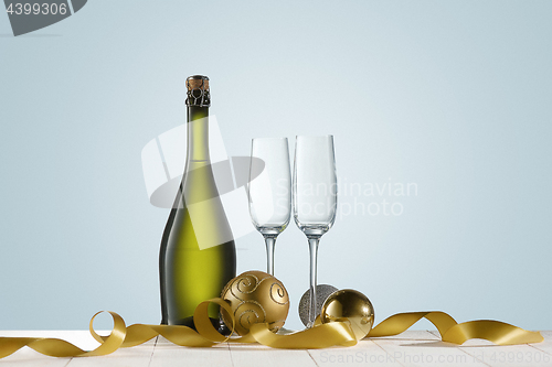 Image of Glasses with champagne and bottle over sparkling holiday background