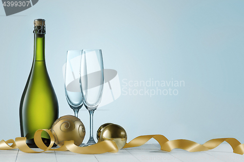 Image of Glasses with champagne and bottle over sparkling holiday background