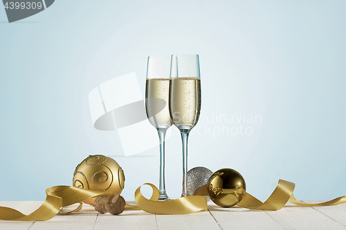 Image of Glasses with champagne and bottle over sparkling holiday background