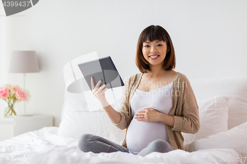 Image of happy pregnant asian woman with tablet pc at home