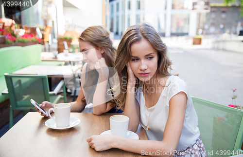 Image of young women with smartphone and coffee at cafe