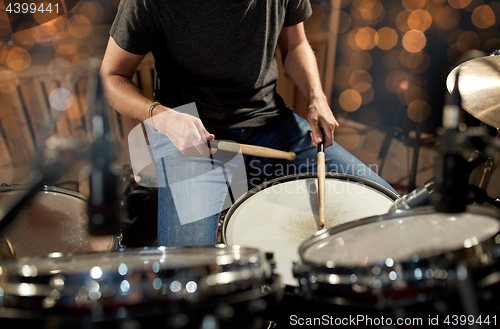 Image of musician playing drum kit at concert over lights