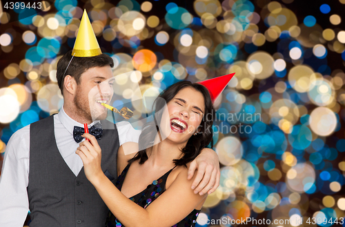 Image of happy couple with party blowers having fun