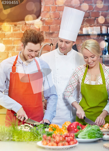 Image of happy couple and male chef cook cooking in kitchen