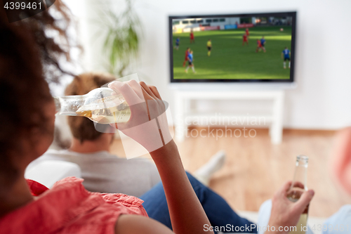 Image of friends drinking beer and watching soccer on tv