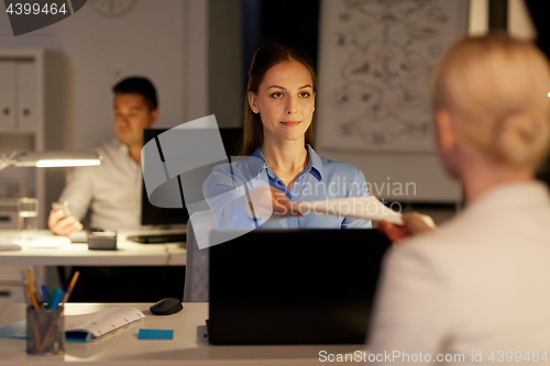 Image of businesswomen with papers working late at office