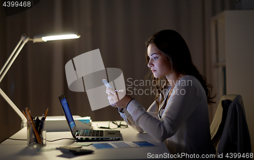 Image of businesswoman with smartphone and laptop at office