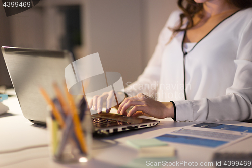 Image of businesswoman with laptop working at night office