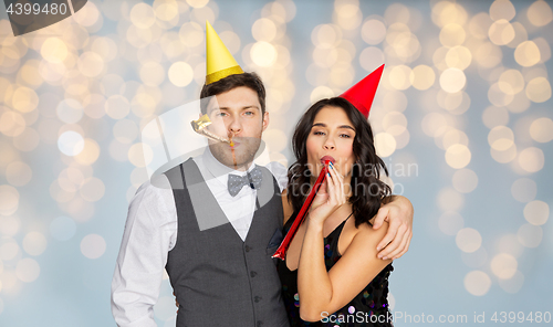 Image of happy couple with party blowers having fun