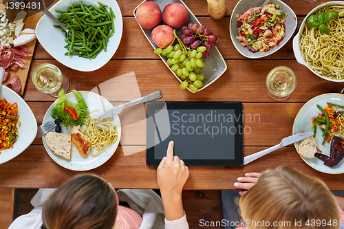 Image of women with tablet pc at table full of food