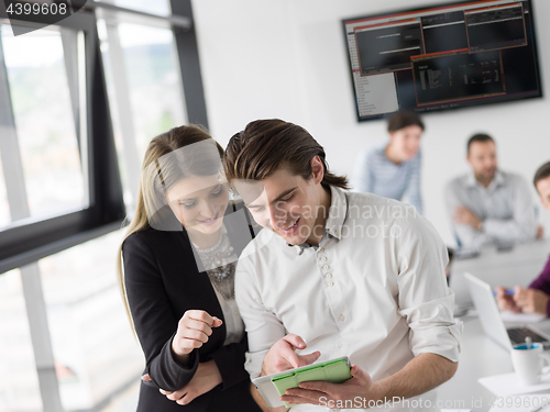 Image of Two Business People Working With Tablet in office