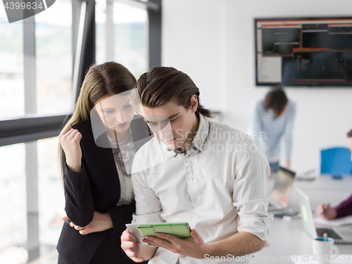 Image of Two Business People Working With Tablet in office