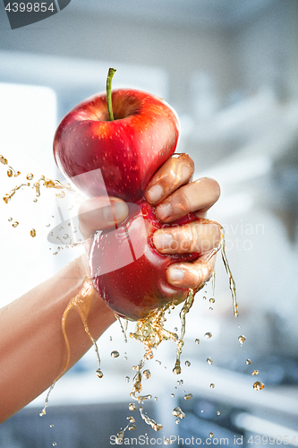 Image of A male hand squeezes fresh juice. Pure apple juice pouring out from fruit into glass