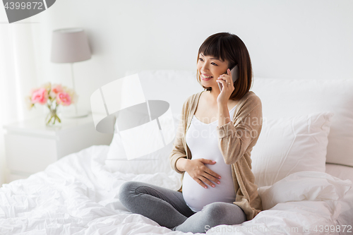 Image of happy pregnant woman calling on smartphone at home