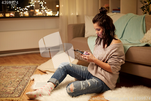 Image of happy young woman with smartphone at home