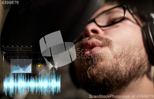 Image of man with headphones singing at recording studio