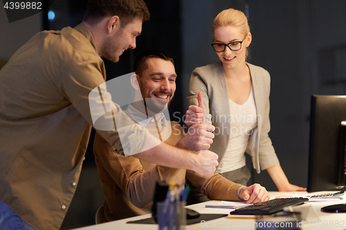 Image of business team making thumbs up gesture at office