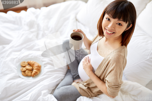 Image of happy pregnant woman with cup drinking tea at home