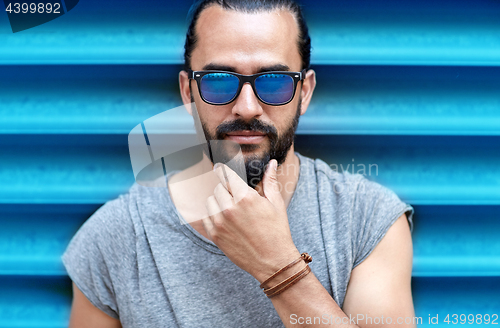 Image of close up of man in sunglasses touching beard