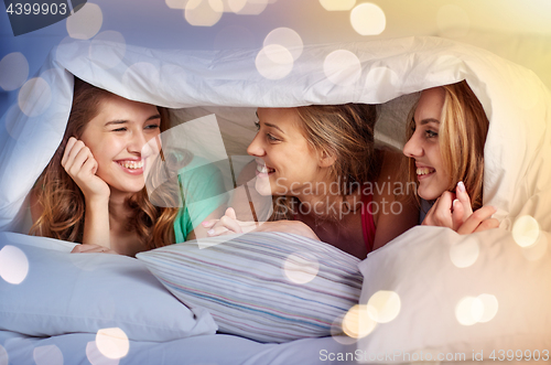 Image of happy young women in bed at home pajama party