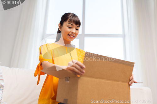 Image of happy asian young woman with parcel box at home