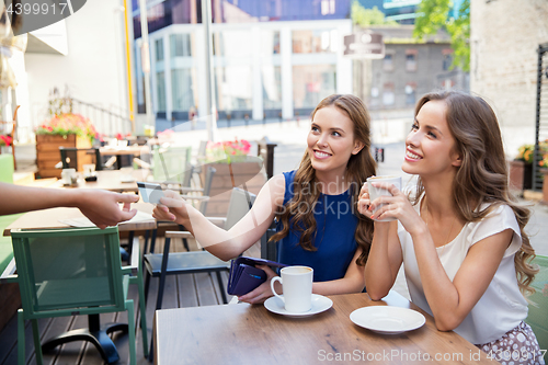 Image of young women paying for coffee at street cafe