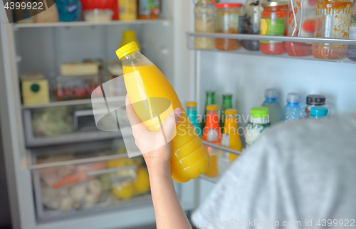 Image of Teenage girl takes the orange juice from the refrigerator