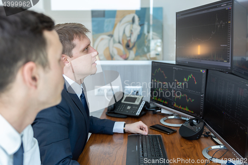 Image of Stock brokers looking at computer screens, trading online.