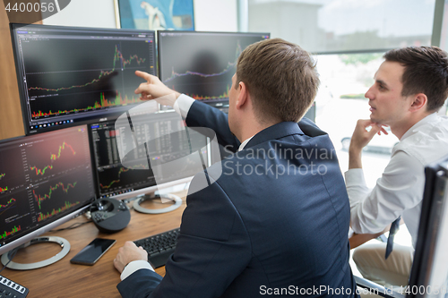 Image of Stock brokers looking at computer screens, trading online.