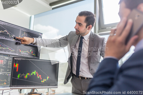 Image of Stock brokers looking at computer screens, trading online.