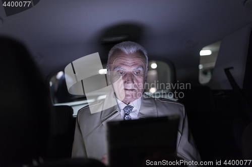 Image of Businessman with a digital tablet sitting in the back seat of a car