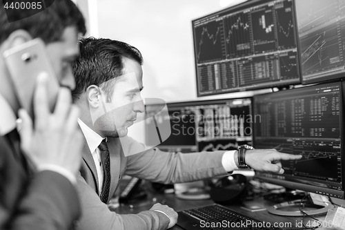 Image of Stock brokers looking at computer screens, trading online.