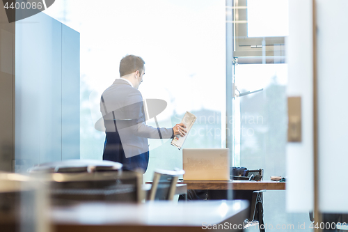 Image of Businessman talking on a mobile phone while looking through window.