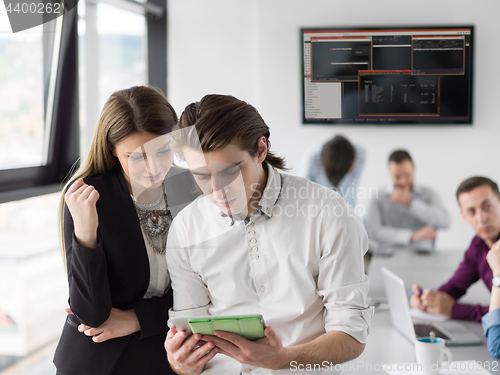 Image of Two Business People Working With Tablet in office