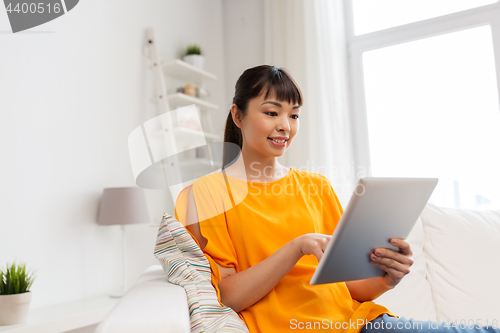 Image of happy young asian woman with tablet pc at home