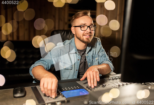 Image of man at mixing console in music recording studio