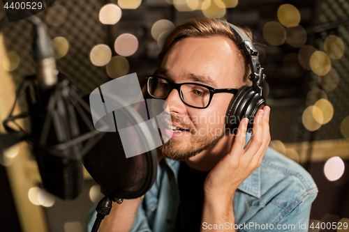 Image of man with headphones singing at recording studio