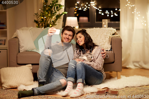 Image of happy couple taking selfie by smartphone at home