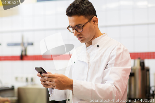 Image of chef cook with smartphone at restaurant kitchen