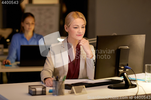 Image of businesswoman at computer working at night office