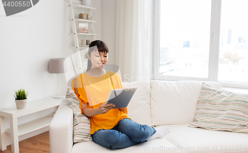 Image of happy young asian woman with tablet pc at home