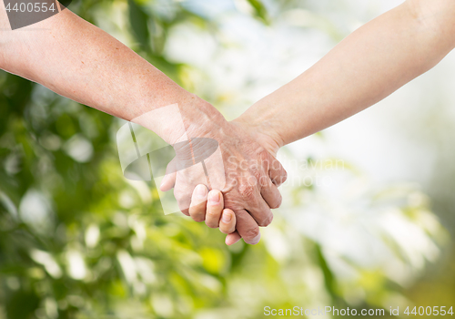 Image of close up of senior and young woman holding hands