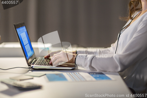 Image of businesswoman with laptop working at night office