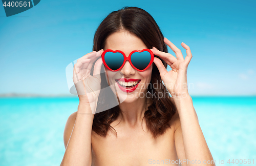 Image of woman with heart shaped shades over sea and sky